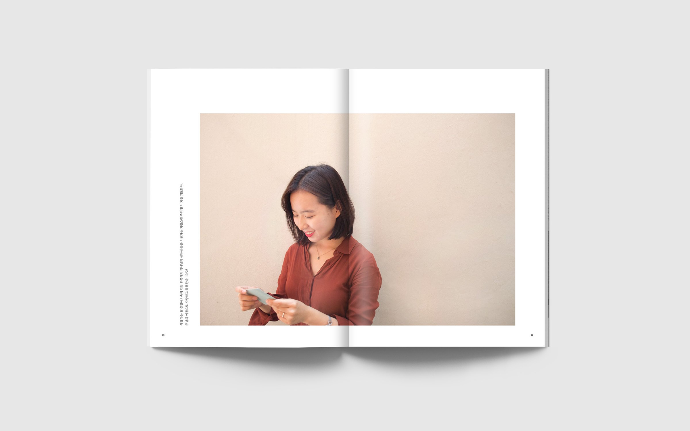 Spread, pages 18–19: a full-width photograph of a smiling woman reading a small card against a pale wall, with a vertical line of text at the left