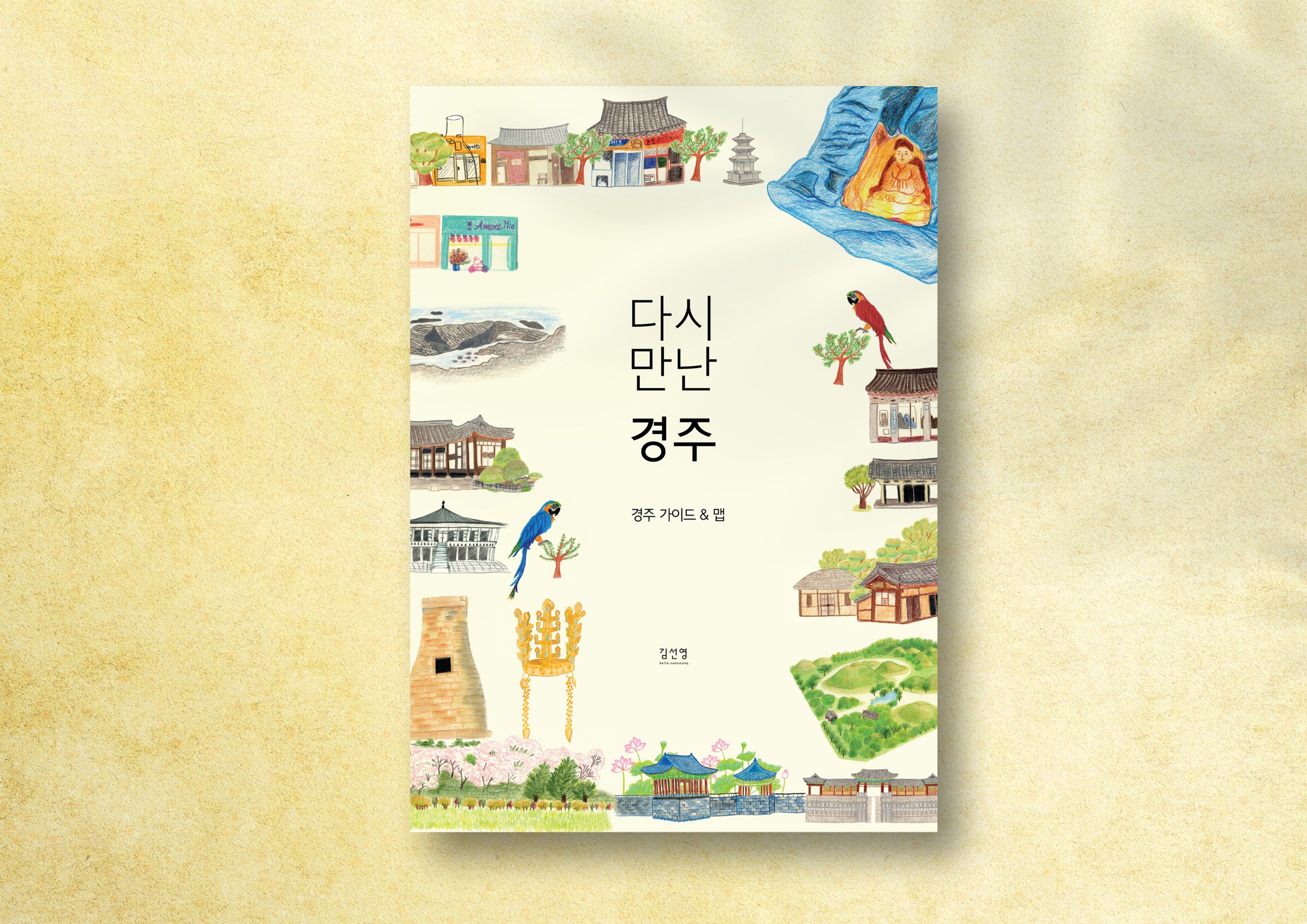 The front cover of the 다시 만난 경주 guide on a warm yellow paper ground: a cream sheet with the title at its centre, framed by small coloured-pencil drawings of Gyeongju landmarks, the Namsan Buddha at upper right and the gold crown at lower left